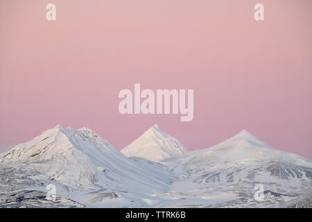 Una vista maestosa di montagne dalle vette innevate contro il cielo drammatico Foto Stock