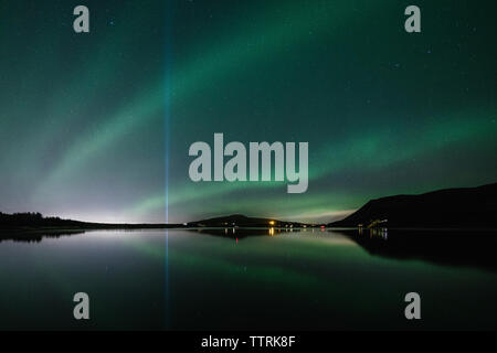 Vista panoramica delle aurore boreali sopra il lago contro il cielo di notte Foto Stock