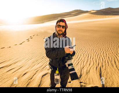 Ritratto di un escursionista azienda smart phone durante il riposo a grandi dune di sabbia del Parco Nazionale Foto Stock