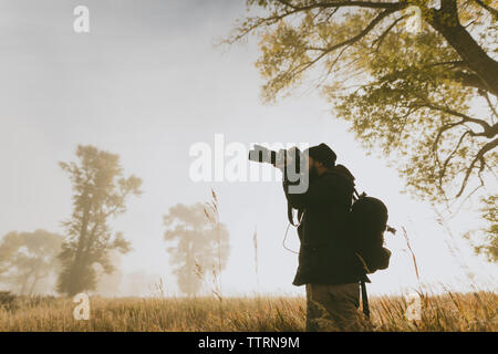 Basso angolo di visione di un escursionista fotografare con la fotocamera mentre si sta in piedi sul campo Foto Stock