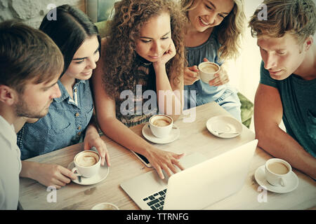Happy amici con il computer portatile di bere il caffè nella caffetteria Foto Stock