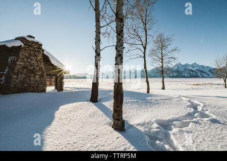 Le tracce nella neve nel cortile di una cabina abbandonata con viste mt Foto Stock