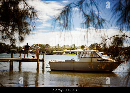 Vista posteriore del senior l uomo e la donna in piedi sul molo in barca ormeggiata sul lago Foto Stock