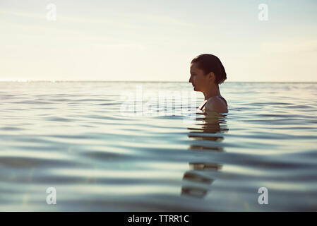 Vista di profilo di premurosa donna in mare contro sky Foto Stock