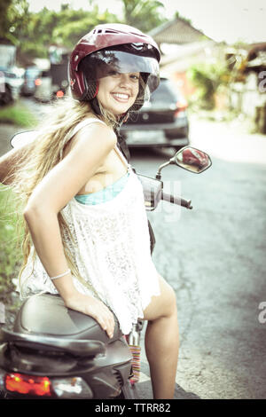 Ritratto di donna sorridente seduto su scooter Foto Stock
