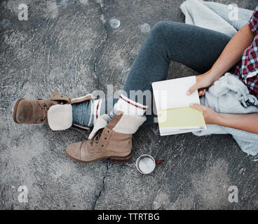 Elevato angolo di visione della donna diario di contenimento mentre è seduto sul lungolago Foto Stock