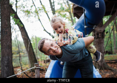 Ritratto di Padre piggybacking figlia al parco giochi Foto Stock