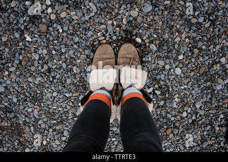 Sezione bassa della donna in piedi su ciottoli in spiaggia Foto Stock