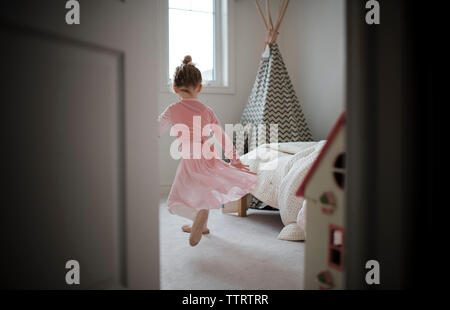 Vista posteriore di una ragazza in costume di balletto dancing at home visto attraverso la porta Foto Stock