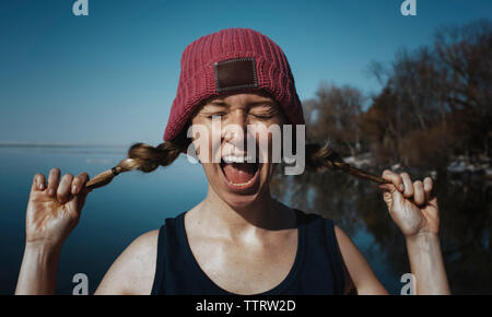 Donna con gli occhi chiusi urlando contro il mare durante la giornata di sole Foto Stock