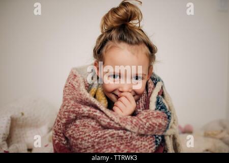 Ritratto di una giovane ragazza avvolto in una coperta con un sorriso Foto Stock