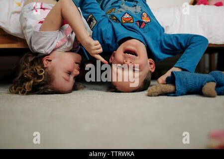 Ragazzo e ragazza fratelli ridere insieme in posizione capovolta sul letto Foto Stock