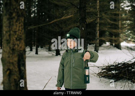 Ragazzo lanterna di contenimento e la torcia in piedi in una coperta di neve forest Foto Stock