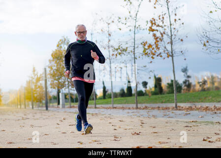 Lunghezza completa di senior uomo jogging durante l esercizio al parco durante l'autunno Foto Stock