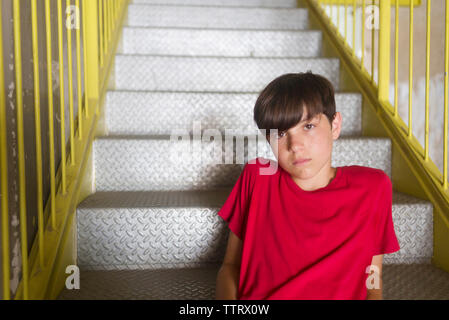 Ritratto di fiducia studente indossando t-shirt rossa seduta su fasi metalliche Foto Stock