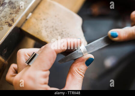 Mani tagliate del gioielliere femmina anello di sagomatura con la raspa in officina Foto Stock