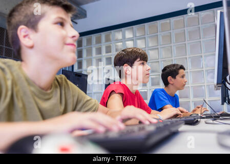 Scolari utilizzando i computer desktop in aula Foto Stock