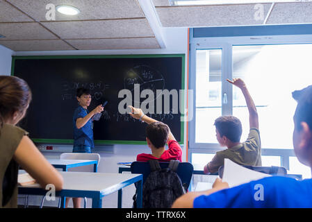 Vista laterale del maestro femmina ad interagire con gli studenti in aula Foto Stock