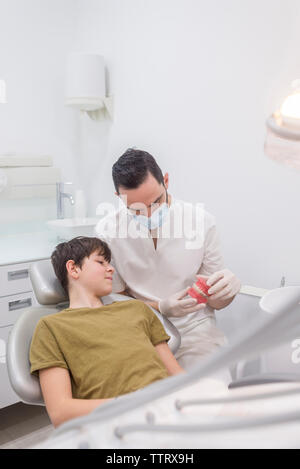 Dentista che mostra a protesi al paziente in clinica Foto Stock