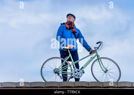 Vista frontale del senior uomo in piedi con la bici mentre cerchi di distanza all'aperto Foto Stock