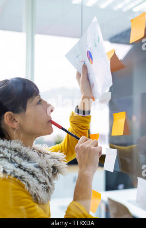 Imprenditrice iscritto sulla finestra in ufficio creativo visto attraverso il vetro Foto Stock