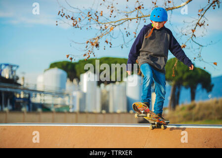 Vista frontale del giovane ragazzo preparato in rampa di skate indossando il casco blu Foto Stock