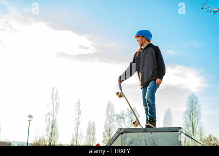 Vista bassa del giovane pattinatore sulla rampa di skate pronto a eseguire un trick Foto Stock