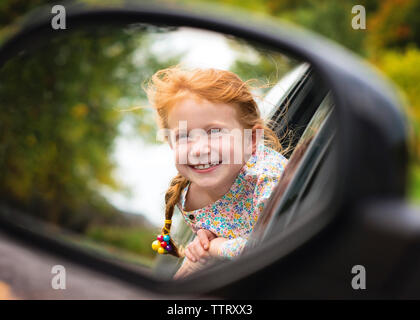 La riflessione di allegro ragazza visto in vista laterale lo specchio Foto Stock