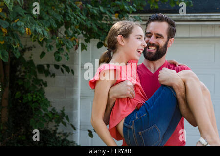 Padre Felice portando la figlia mentre si sta in piedi in cantiere Foto Stock