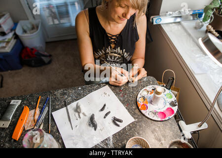 Angolo di Alta Vista della femmina colorazione dello scultore scultura scrivania in officina Foto Stock