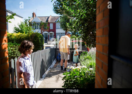 Ragazzo che guarda al nonno di parlare al nipote permanente, mentre in cantiere durante la giornata di sole Foto Stock