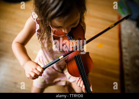 Angolo di Alta Vista della ragazza suona il violino mentre è seduto a casa Foto Stock