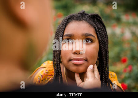 Immagine ritagliata della madre con la mano sulla mia figlia mento permanente al park Foto Stock