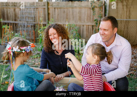 Due bambine giocare mentre i loro genitori guarda con affetto in Foto Stock