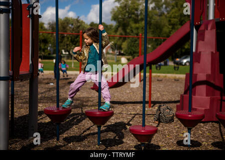 Un orgoglioso indipendente di bambina si arrampica su un parco giochi Foto Stock
