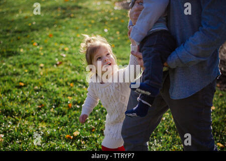 Una bambina raggiunge fino a tenere il suo fratellino la mano Foto Stock