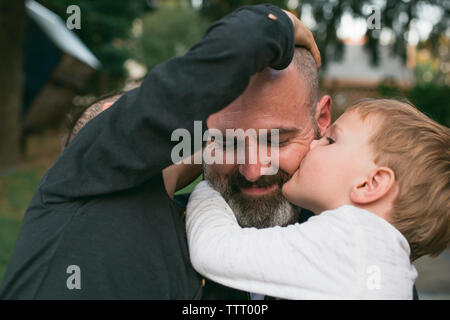 Un padre Felice è baciato dai suoi due bambini piccoli Foto Stock