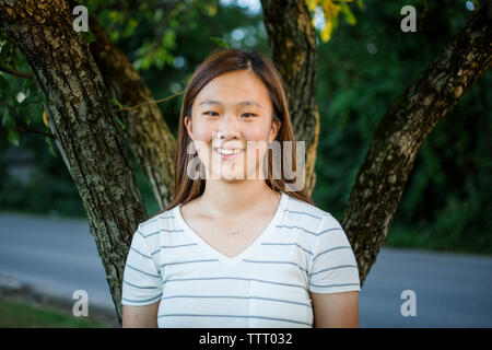 Close-up ritratto di una ragazza adolescente contro un albero in un parco Foto Stock