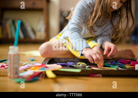 Vista ravvicinata di un piccolo bambino di fare arte sul pavimento nella luce della finestra Foto Stock