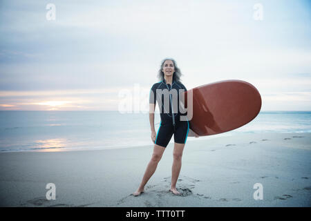 A piena lunghezza Ritratto di fiducioso surfista femmina che trasportano le tavole da surf a Delray Beach Foto Stock