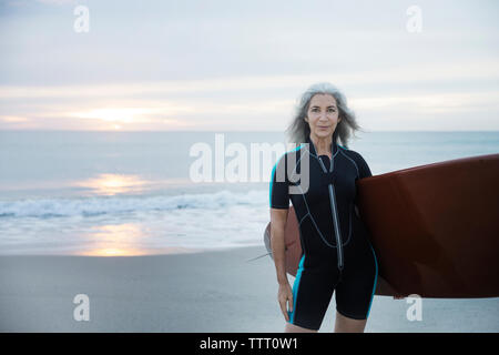 Ritratto di fiducioso surfista femmina che trasportano le tavole da surf a Delray Beach Foto Stock