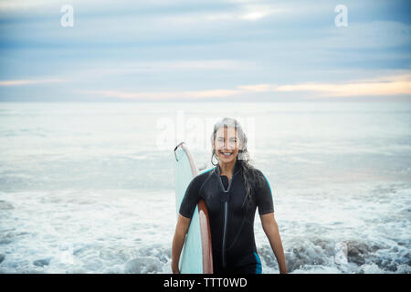 Ritratto di felice bagnato surfista femmina che trasportano le tavole da surf a Delray Beach Foto Stock