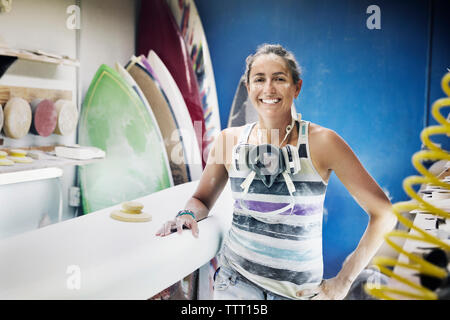 Ritratto di donna felice in piedi nel workshop per le tavole da surf Foto Stock