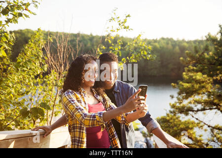 Coppia felice tenendo selfie attraverso smart phone sul lungolago Foto Stock