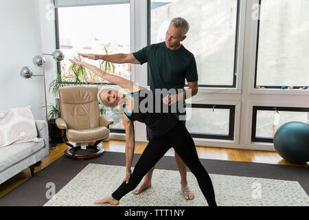 Uomo Donna che assiste a praticare yoga a casa Foto Stock
