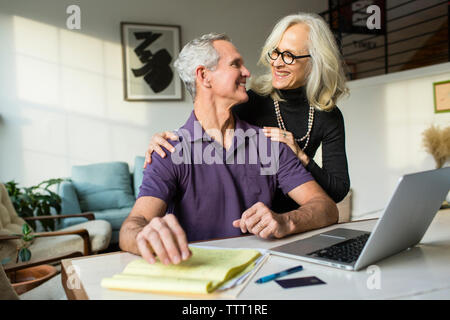 Coppia sorridente cercando ogni altra faccia a faccia mentre si utilizza il computer portatile a casa Foto Stock