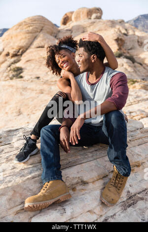 Felice coppia seduta sulla formazione di roccia Foto Stock