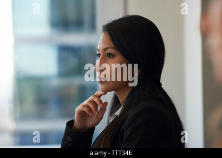 Riflessivo imprenditrice guardando attraverso la finestrella in office Foto Stock