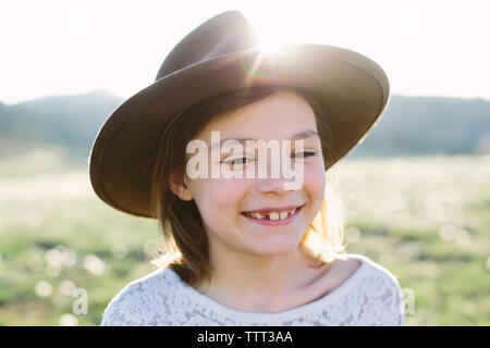 Close-up di felice ragazza indossando hat mentre in piedi contro il cielo durante la giornata di sole Foto Stock