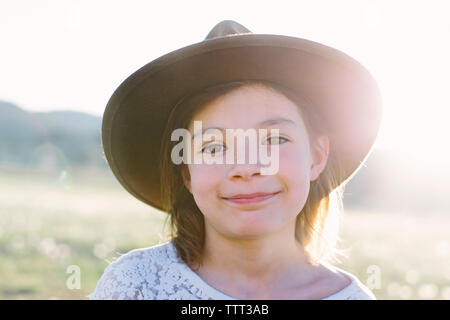 Close-up verticale di felice ragazza indossando hat mentre in piedi contro il cielo durante la giornata di sole Foto Stock